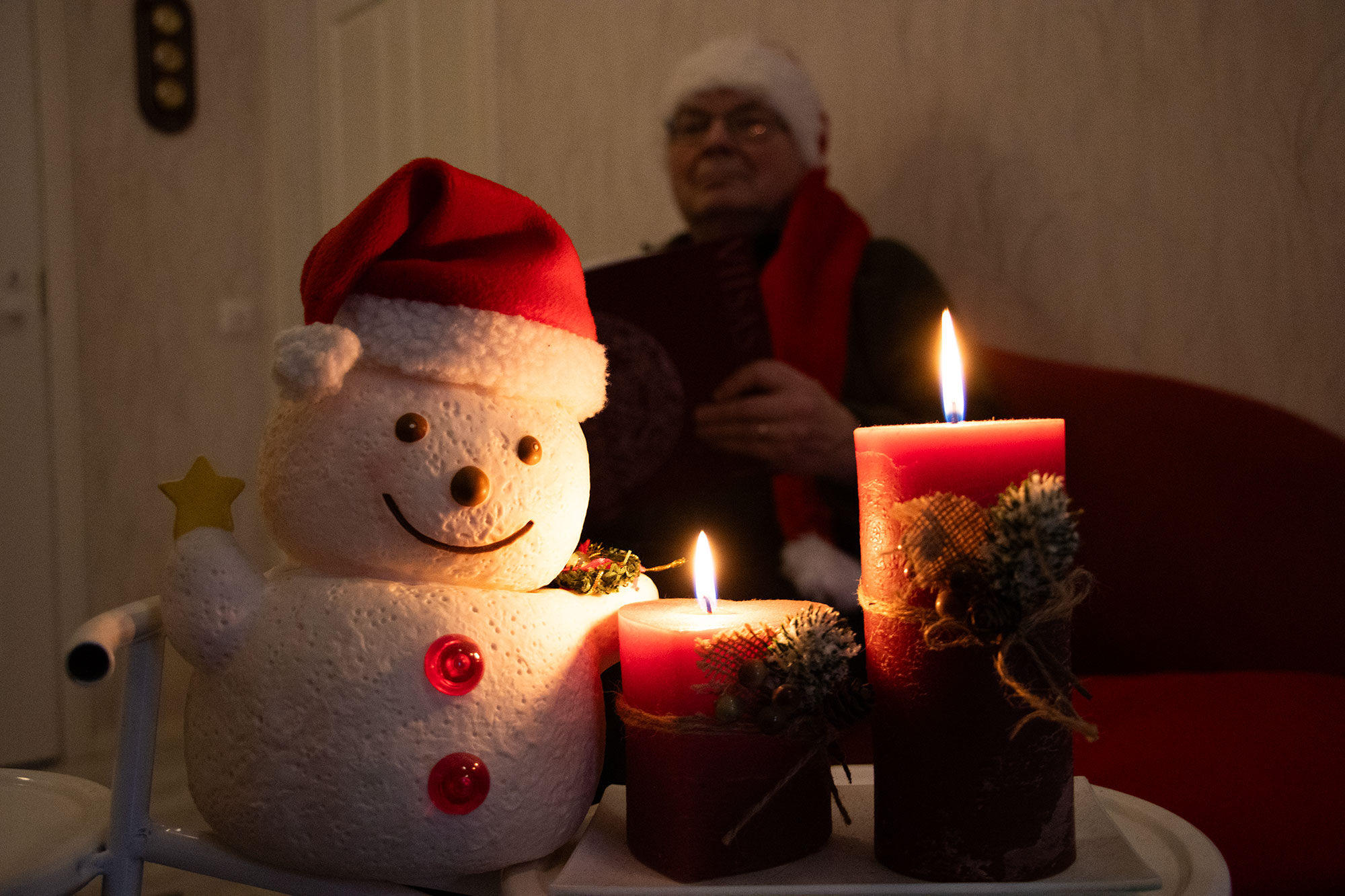 Mofa (Jyrki Grönlund) lukee kirjaa kynttilän ja lumiukon takana.